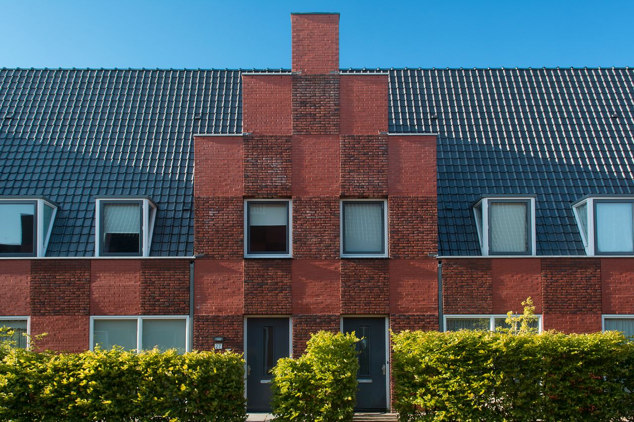 home-services-02 Contemporary brick townhouse facade with neat hedge under clear blue sky.