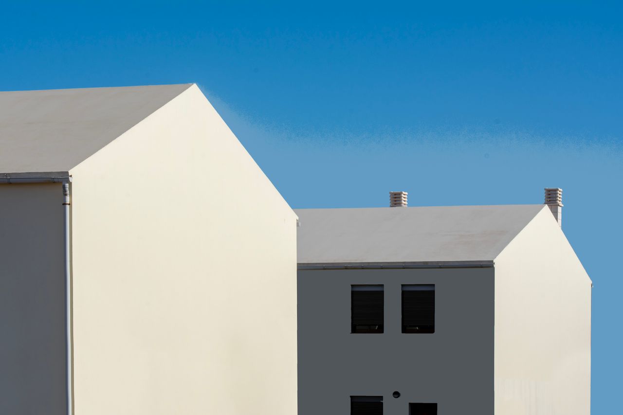 about-01 Contemporary minimalist architecture with white houses contrasting a vivid blue sky.