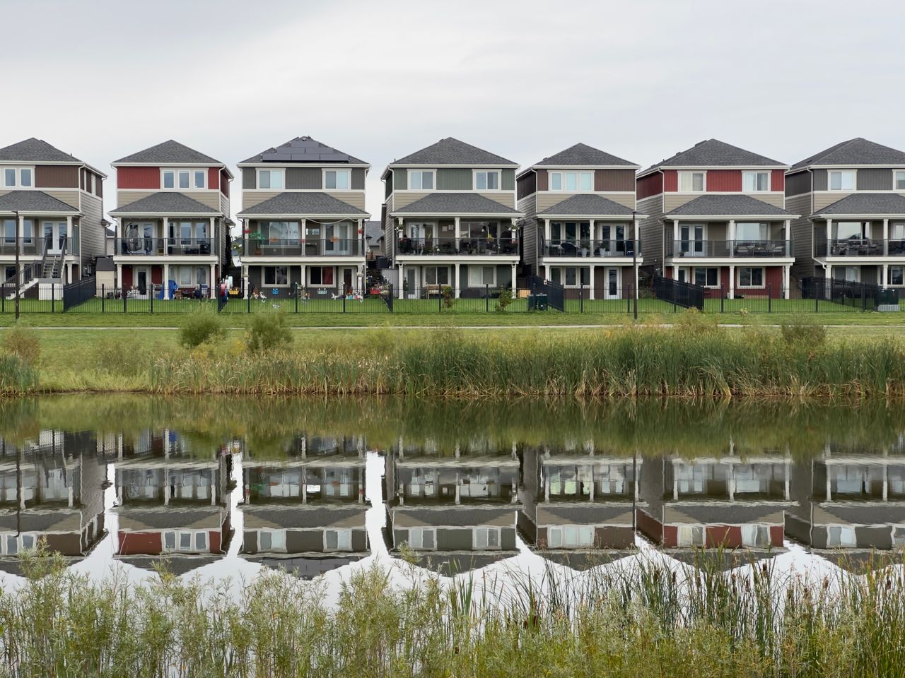 home-hero-bg A row of modern houses reflected in a calm pond, showcasing serene suburban architecture.