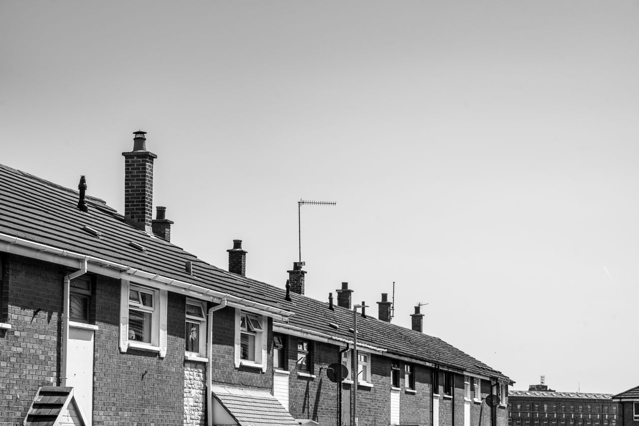 home-services-004 Monochrome view of classic Irish residential row houses with chimneys under a clear sky.