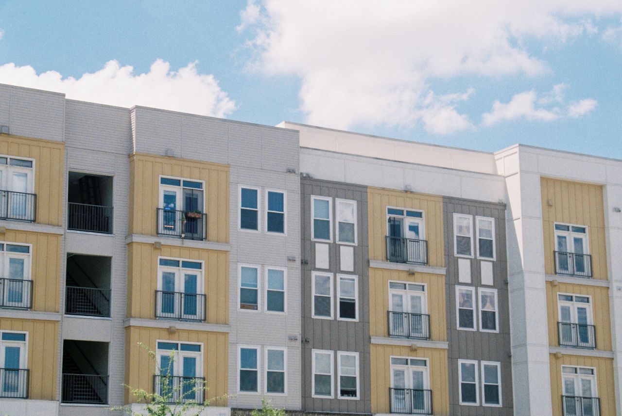 home-services-01 Contemporary apartment building exterior with yellow and grey panels under a clear blue sky.